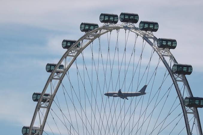 Singapore Flyer capsules along the white rim against a blue sky