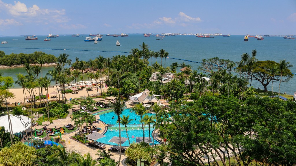 Resort pool and palm trees on Sentosa with cargo ships on the Singapore Strait